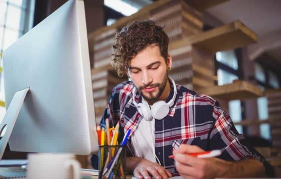 A&R Administrator sitting at desk with headphones around his neck
