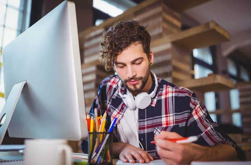 A&R Administrator sitting at desk with headphones around his neck