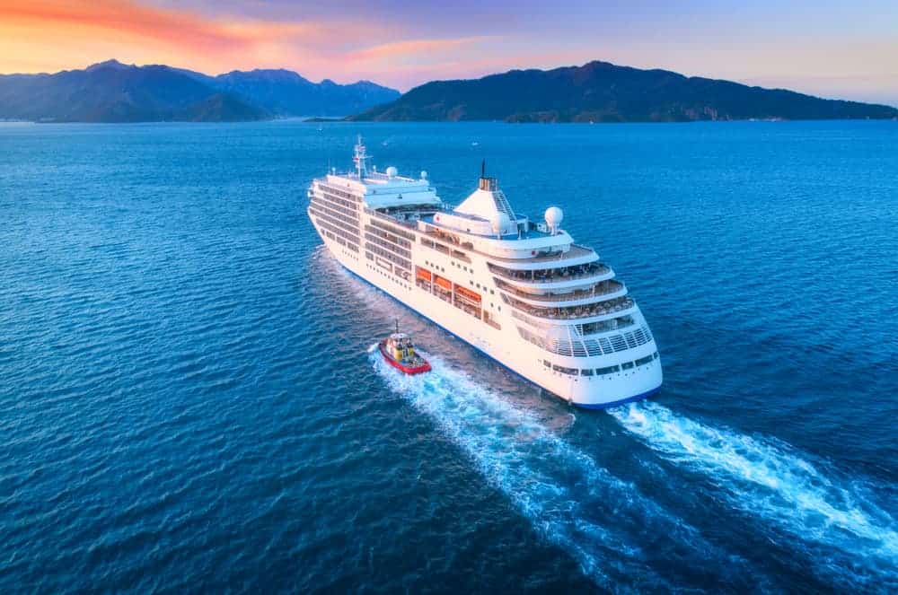 Cruise ship with smaller boat on the ocean near mountains