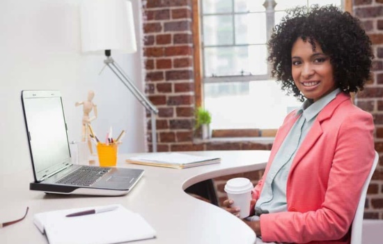 Stylish female Director of Publicity drinking coffee at her desk