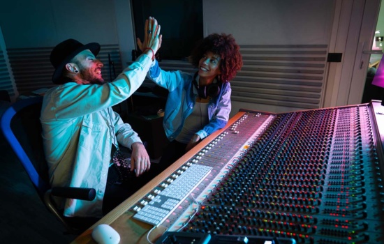 Two male music interns getting feedback from their older female supervisor