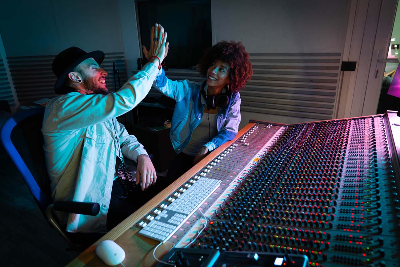 Two male music interns getting feedback from their older female supervisor