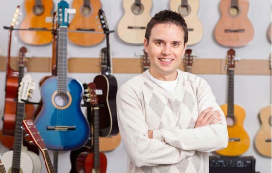 Music Store Manager standing in music store with rows of acoustic guitars