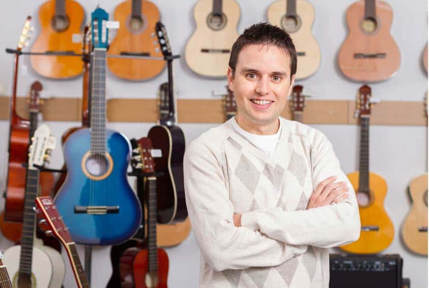 Music Store Manager standing in music store with rows of acoustic guitars