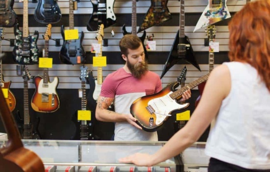Music Store Salesperson showing electric guitar to female customer