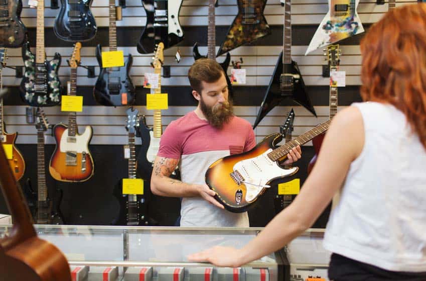 Music Store Salesperson showing electric guitar to female customer