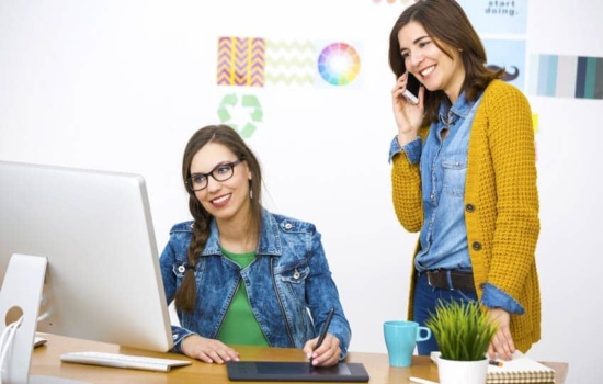 Two Website Marketing Managers look at a computer and iPad in the office