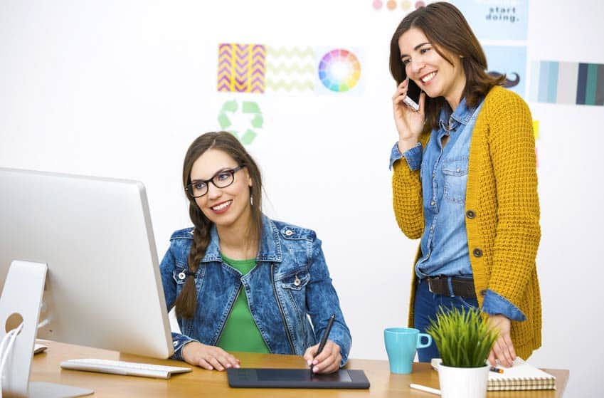 Two Website Marketing Managers look at a computer and iPad in the office