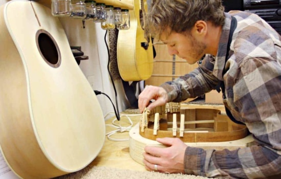 Musical Instrument Builder and Developer assembling acoustic guitar in his workshop