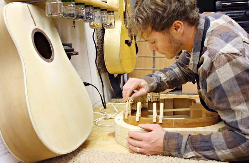 Musical Instrument Builder and Developer assembling acoustic guitar in his workshop