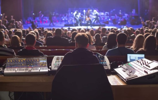 Sound technician working on the mixing console in large concert arena