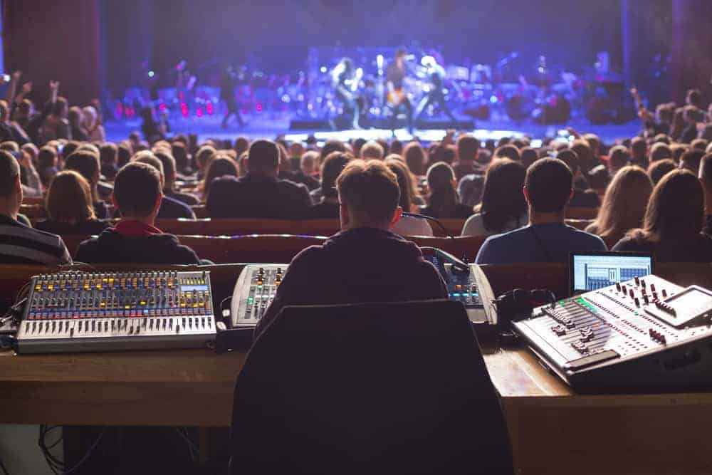 Sound technician working on the mixing console in large concert arena