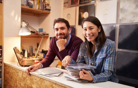 Two record label employees with vinyl releases on the wall behind them