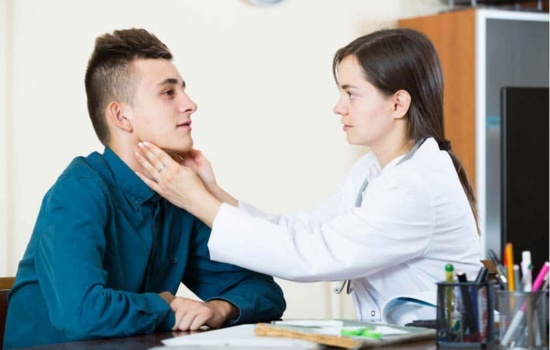 Voice Therapist touching the throat of young male patient