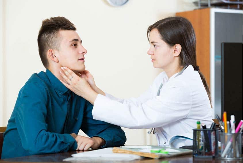 Voice Therapist touching the throat of young male patient