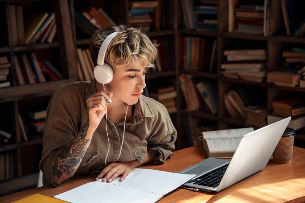 Lyricist listening to music and writing ideas in her notebook