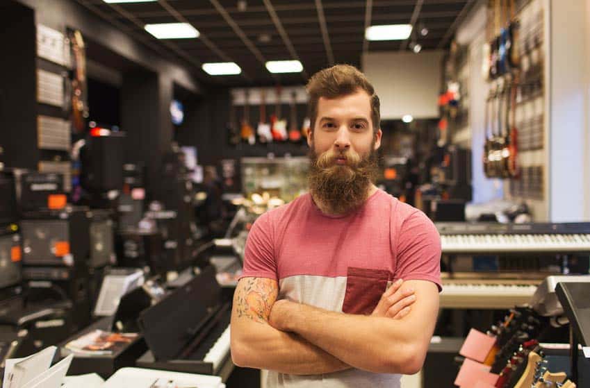 Bearded young man working at the musical instrument store
