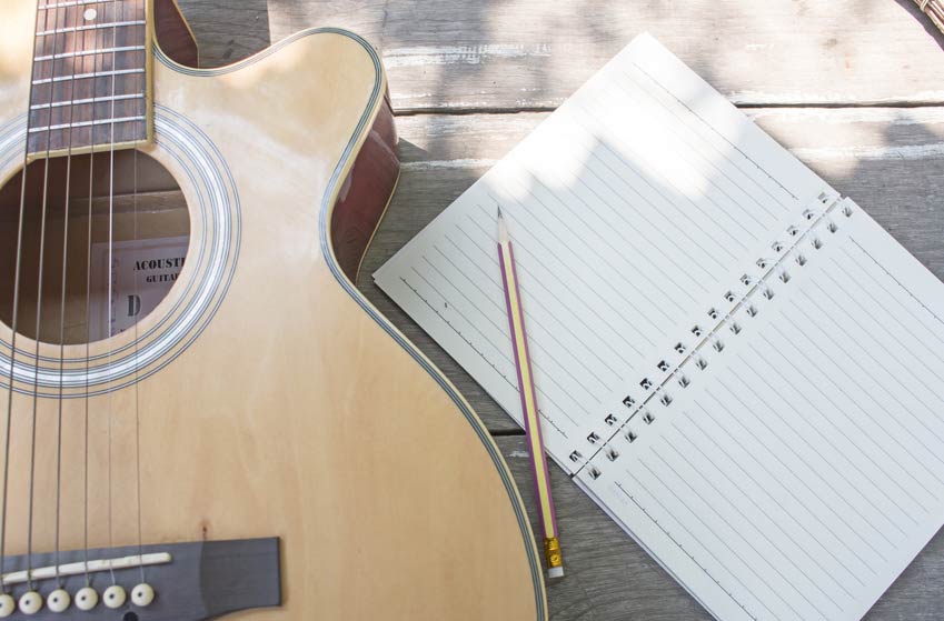 Acoustic guitar and notebook on wood table
