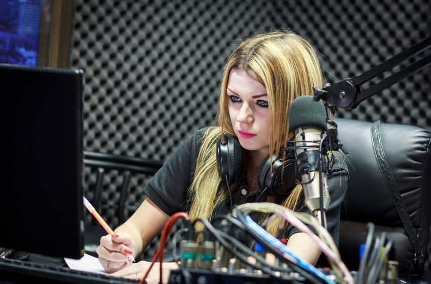 Music Director with headphones around her neck in the on-air studio at the radio station