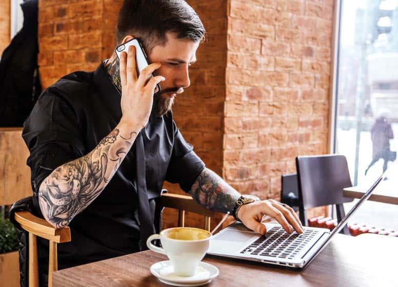 Business Manager looking at his laptop and talking on the phone in a cafe