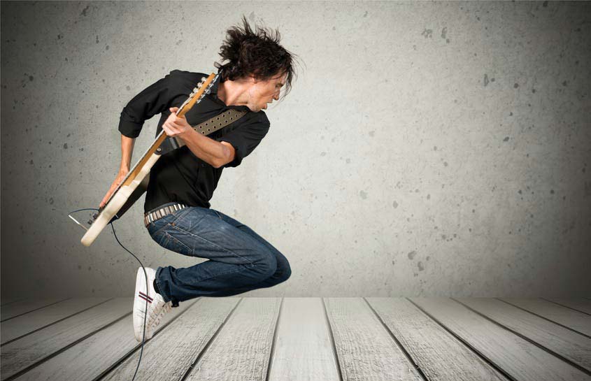 Guitar player jumping in empty room
