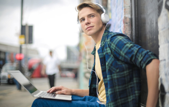 Young male musician listening to songs on his laptop