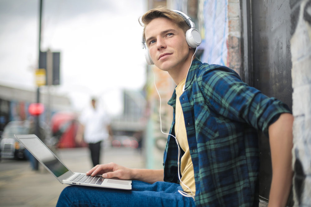 Young male musician listening to songs on his laptop