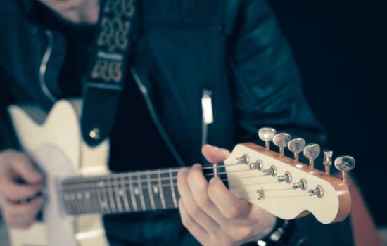 Guitar Technician tuning up guitar in closeup shot