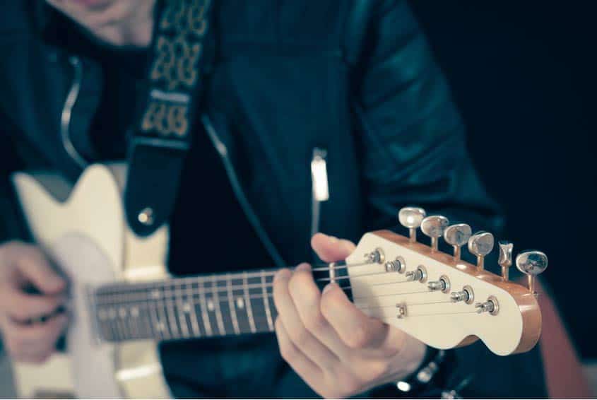 Guitar Technician tuning up guitar in closeup shot