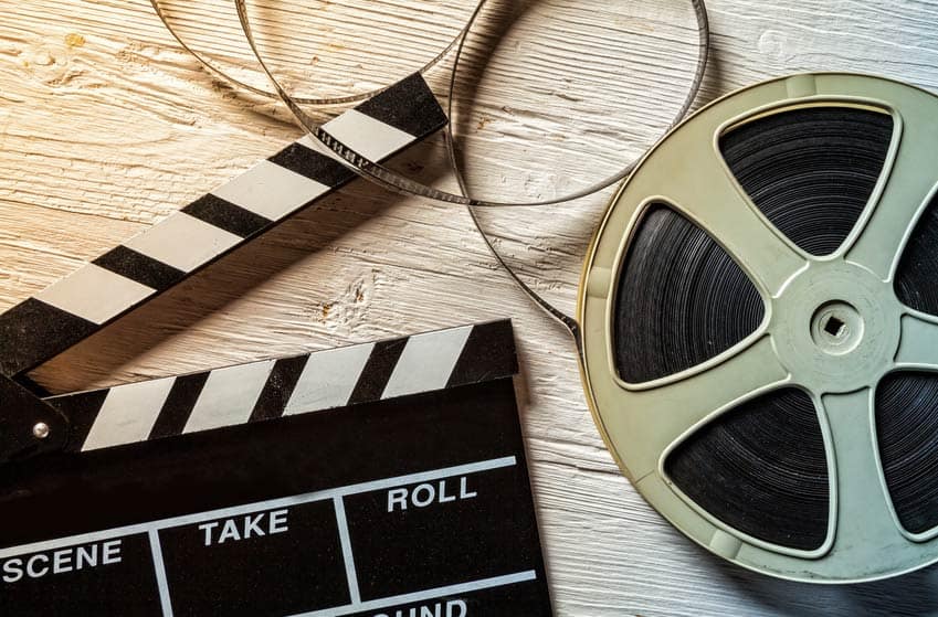 Film clapperboard and roll of film on wooden background