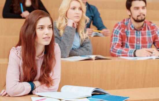 Female college student smiles during lecture with other classmates