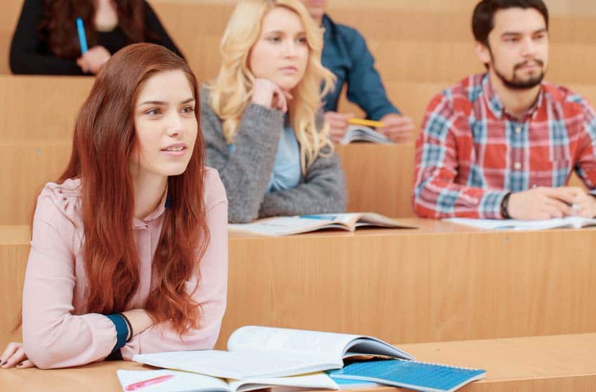 Female college student smiles during lecture with other classmates