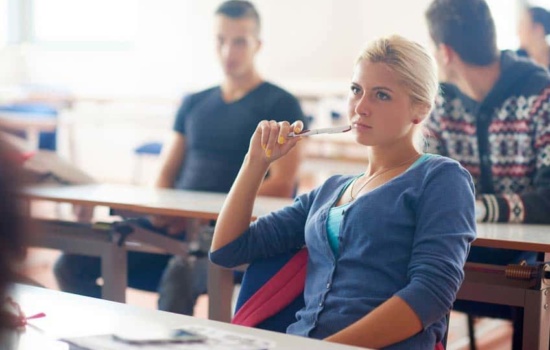 Young blonde female college student listening to a class discussion
