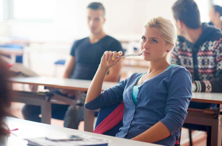 Young blonde female college student listening to a class discussion