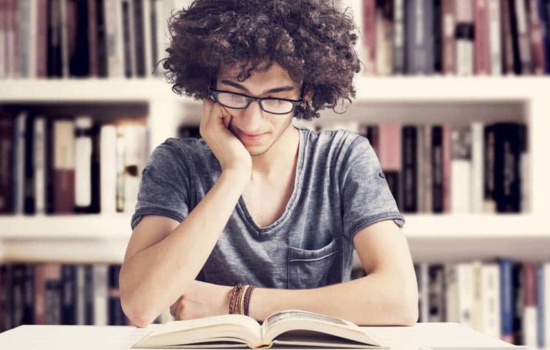 Young man reading a music book in the library