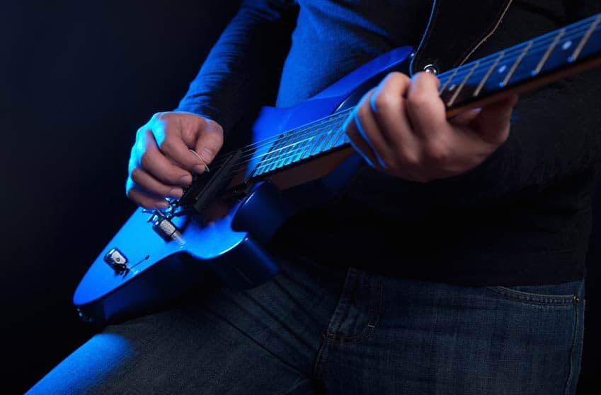 Closeup of musician playing blue electric guitar