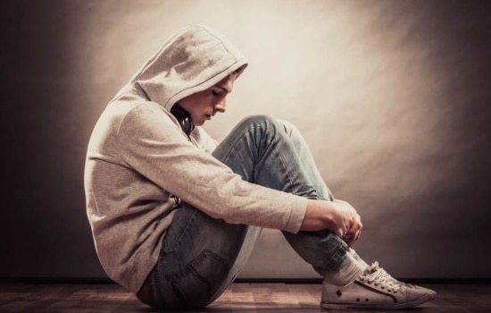 Musician with headphones holding his knees and looking sad