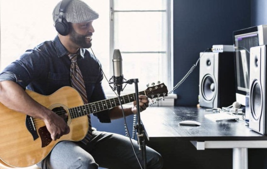Jingle writer composing a guitar tune in his home recording studio