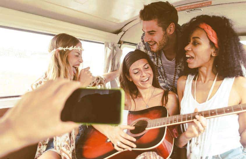 Bandmates shooting a photo for Instagram in the back of their tour van