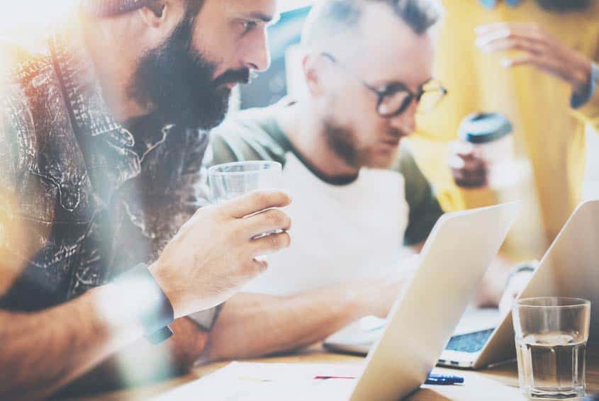Two bandmates writing their band bio on their laptops