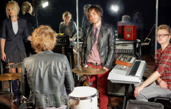 Musicians at band practice discussing how to get their music heard