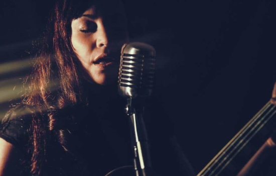 Female musician playing guitar and singing into microphone