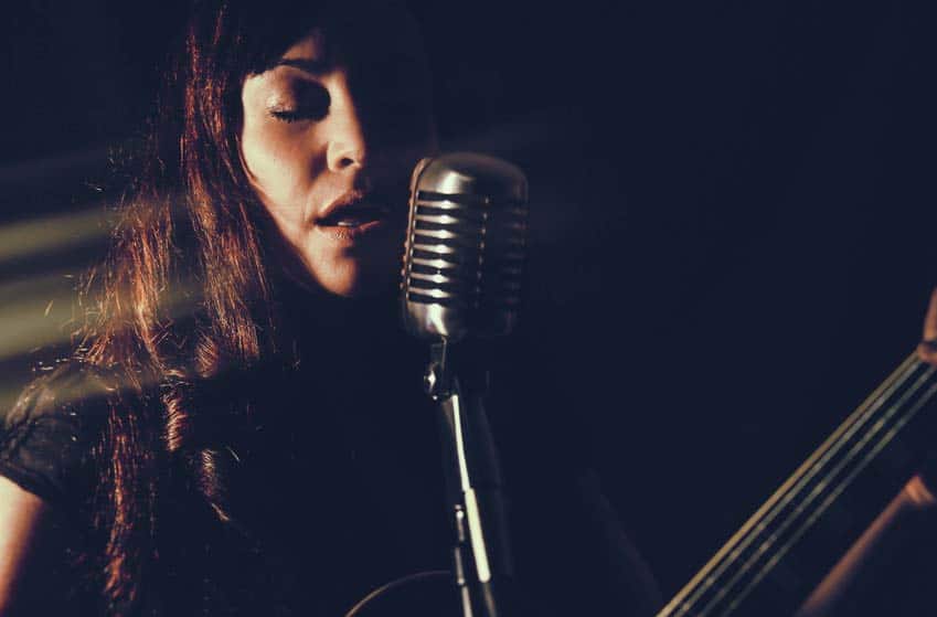 Female musician playing guitar and singing into microphone