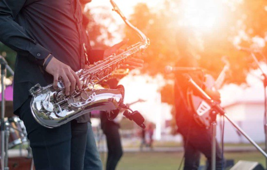 Jazz musician playing saxophone at outdoor concert with bandmates