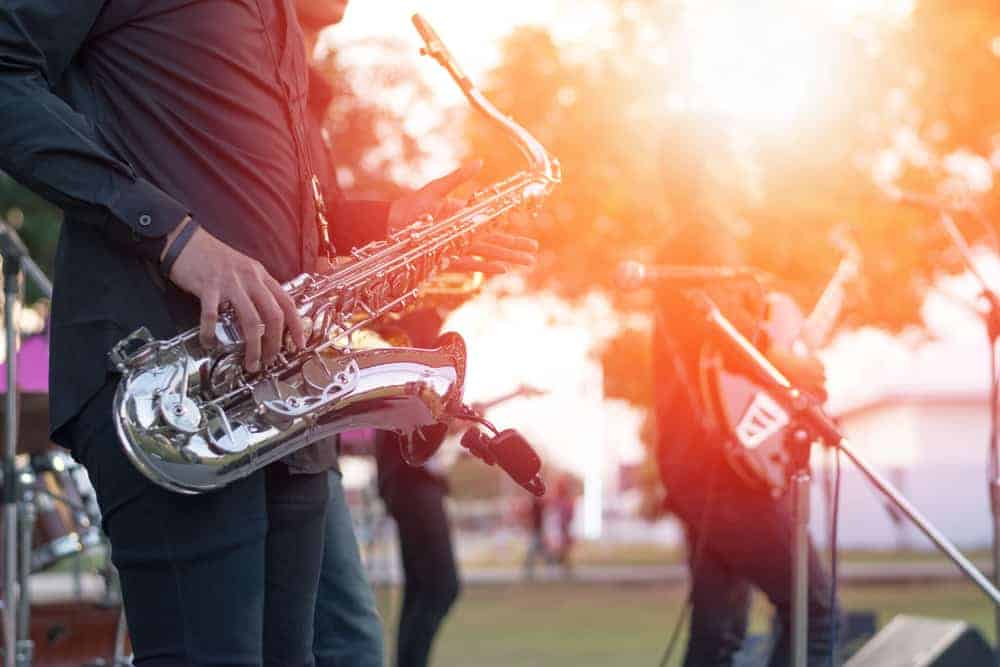 Jazz musician playing saxophone at outdoor concert with bandmates
