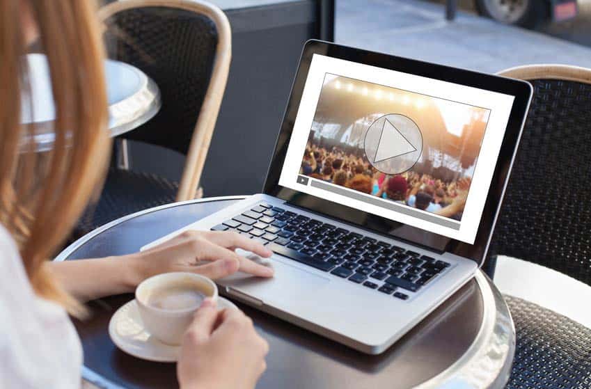 Young woman watching a music festival performance on her laptop