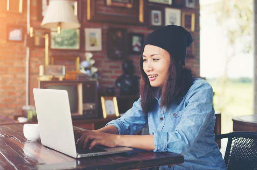 Young Asian female musician using her laptop in a coffee shop