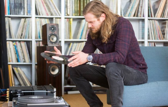 Young male vinyl collector reading the label on one of his records