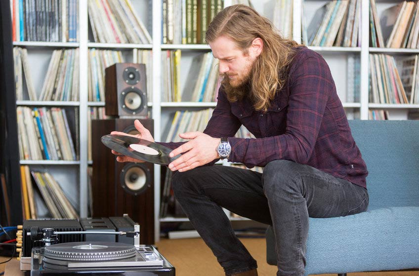 Young male vinyl collector reading the label on one of his records