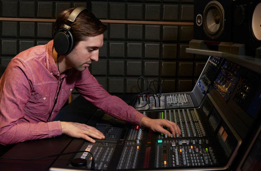 Mastering engineer using mixing console in recording studio